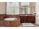 Elegant bathroom with a soaking tub, marble countertops, custom vanity, and plantation shutters for natural light at 42109 N Astoria Way, Anthem, AZ 85086