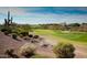 Beautiful golf course view with lush green grass, desert landscaping, and a view of homes in the distance at 42109 N Astoria Way, Anthem, AZ 85086