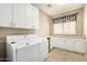 Well-equipped laundry room with white cabinets, washer, dryer, and a window at 42109 N Astoria Way, Anthem, AZ 85086