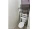 Small bathroom featuring a white toilet with a black metal shelf above it and patterned wallpaper at 44899 W Portabello Rd, Maricopa, AZ 85139