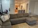 Open-concept living room with a gray sectional sofa that leads to a kitchen with barstool seating at 44899 W Portabello Rd, Maricopa, AZ 85139