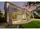 Home's backyard showcasing a covered patio, lush grass, and manicured landscaping against a colorful sky at 4494 E Reins Rd, Gilbert, AZ 85297