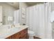 Well-lit bathroom featuring a single sink vanity with wood cabinetry and a shower with white curtain at 4494 E Reins Rd, Gilbert, AZ 85297