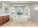 Bright bathroom features a luxurious soaking tub under bay windows and a vanity with wood cabinets at 4494 E Reins Rd, Gilbert, AZ 85297