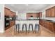 Open-concept kitchen with bar seating, dark countertops, wood cabinets, and stainless steel appliances at 4494 E Reins Rd, Gilbert, AZ 85297
