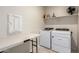 This laundry room features a folding table, shelving, and modern appliances at 5079 E Emery Rd, San Tan Valley, AZ 85143