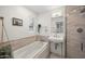 Bright bathroom featuring a soaking tub with tile surround and a pedestal sink with modern fixtures at 5812 N 18Th Pl, Phoenix, AZ 85016