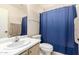 Well-lit bathroom featuring a blue shower curtain, white vanity, and ample space at 9662 W Sunnyslope Ln, Peoria, AZ 85345