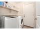 Functional laundry room with modern washer and dryer units, shelving, and easy access to the exterior at 9662 W Sunnyslope Ln, Peoria, AZ 85345