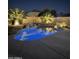 Backyard pool with stone waterfall feature is illuminated at night, surrounded by palm trees at 9662 W Sunnyslope Ln, Peoria, AZ 85345