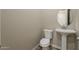 Powder room featuring pedestal sink, round mirror, and toilet with neutral walls and tile floors at 34865 N Palm Dr, San Tan Valley, AZ 85140