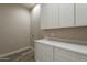 The laundry room boasts white shaker cabinets, quartz counters and wood look flooring at 34865 N Palm Dr, San Tan Valley, AZ 85140