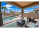 Inviting covered patio with comfortable seating overlooks a private backyard oasis with a pool and waterfall feature at 3671 E Kingbird Pl, Chandler, AZ 85286