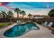 Backyard pool with a waterfall feature, lounge chairs, and palm trees creates a relaxing oasis at 3671 E Kingbird Pl, Chandler, AZ 85286