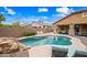 This backyard boasts a pool with a rock waterfall, a covered patio, and lounge seating at 3671 E Kingbird Pl, Chandler, AZ 85286