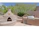 Custom outdoor kitchen area with a pizza oven, built-in grill, and lush desert landscape at 6714 E Amber Sun Dr, Scottsdale, AZ 85266