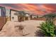 Spacious backyard with desert landscape, covered patio, and mature trees under a colorful sky at 9423 W Monte Vista Rd, Phoenix, AZ 85037