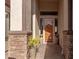 Covered front porch with decorative stone pillars, potted plants, and an inviting wood door with glass accents at 1019 N Tambor Cir, Mesa, AZ 85207