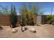 Backyard desert landscape design featuring native plants, shed, and artistic water pump and wagon wheel at 18436 W Shasta St, Goodyear, AZ 85338