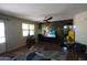 Open-concept living room with wood floors, ceiling fan, and a large entertainment center at 18436 W Shasta St, Goodyear, AZ 85338