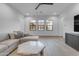 Bright living room with a large sofa, modern ceiling fan, wood floors and plenty of natural light from three windows at 3981 E Runaway Bay Pl, Queen Creek, AZ 85142