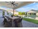Covered patio with dining table, ceiling fan, outdoor kitchen, pool, fire pit and green turf at 3981 E Runaway Bay Pl, Queen Creek, AZ 85142