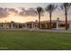 Expansive modern home with lush green lawn, desert landscaping, and soaring palm trees at sunset at 6633 E Horseshoe Rd, Paradise Valley, AZ 85253