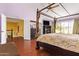 Bedroom with four-poster bed, wood floors, and access to outdoor balcony showcasing light-filled open space at 21483 N 65Th Ave, Glendale, AZ 85308