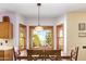 Dining area with a bay window offering views of the landscaped backyard and mature trees at 21483 N 65Th Ave, Glendale, AZ 85308