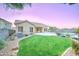 Twilight view of the house and backyard features a lawn, a patio, and a pool at 329 S Marin Dr, Gilbert, AZ 85296