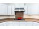 Close-up view of kitchen cooktop, granite countertops, white cabinetry, and stainless steel vent hood at 404 E Coconino Pl, Chandler, AZ 85249