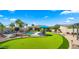 Beautiful backyard featuring a putting green, pool, covered patio, and lush landscaping, perfect for relaxing at 4865 S Cylinder Way, Mesa, AZ 85212