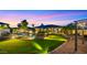 Beautiful backyard with lush lawn, sparkling pool, fire pit, lounge seating, and evening sky at 4865 S Cylinder Way, Mesa, AZ 85212