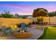 Inviting fire pit area with comfortable seating, adjacent to a dining area and a beautifully landscaped backyard at 4865 S Cylinder Way, Mesa, AZ 85212