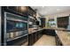 Gourmet kitchen features stainless steel appliances, dark cabinetry, and stone countertops at 4865 S Cylinder Way, Mesa, AZ 85212