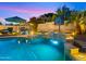 Stunning pool area with a rock waterfall feature, basketball hoop, lounge seating, and ambient lighting at 4865 S Cylinder Way, Mesa, AZ 85212