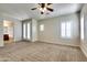 Spacious bedroom featuring a ceiling fan, neutral carpet, and bright, shuttered windows at 15387 W Columbine Dr, Surprise, AZ 85379
