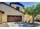 Two-story home showcasing tan stucco and brown trim, with a spacious two car garage and ample shade trees at 15387 W Columbine Dr, Surprise, AZ 85379