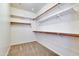 Empty walk-in closet with carpeted floor, wooden bars and white shelves at 15387 W Columbine Dr, Surprise, AZ 85379