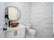 Elegant powder room showcasing a round mirror, unique vessel sink, and stylish marble-like wall tiles at 16368 W Watkins St, Goodyear, AZ 85338