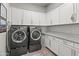 Spacious laundry room featuring modern washer and dryer units, ample storage cabinets, and granite countertops at 18129 N 65Th Pl, Phoenix, AZ 85054