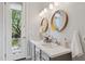 Bathroom showcasing a double sink vanity with modern fixtures, round mirrors, and an exterior door at 28045 N 112Th Pl, Scottsdale, AZ 85262