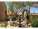 Beautiful garden featuring a stone arch, blooming plants, mature trees, and a charming fountain at 28045 N 112Th Pl, Scottsdale, AZ 85262
