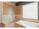 Tiled bathroom with a walk-in shower, soaking tub, and a large window at 8703 E Nora St, Mesa, AZ 85207