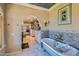 Open bathroom features marble floors, bathtub with silver fixtures, blue accents, and an adjoining bedroom at 12240 S Honah Lee Ct, Phoenix, AZ 85044