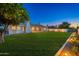 Landscaped backyard with green lawn and patio, all lit up at dusk at 2178 E La Jolla Dr, Tempe, AZ 85282