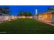 View of back yard with plush green grass, perimeter landscape lights and manicured trees at 2178 E La Jolla Dr, Tempe, AZ 85282