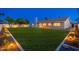 Beautifully landscaped back yard with lush green lawn, patio, and exterior lighting at dusk at 2178 E La Jolla Dr, Tempe, AZ 85282