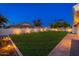 Spacious back yard features green lawn, landscape lighting, and mature trees at dusk at 2178 E La Jolla Dr, Tempe, AZ 85282
