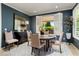 Elegant dining room with a round table, stylish chairs, and views to an outdoor patio through white shuttered windows at 27067 W Sequoia Dr, Buckeye, AZ 85396